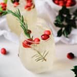 orange moctail garnished with cranberries and rosemary