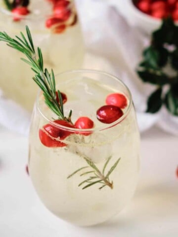 orange moctail garnished with cranberries and rosemary