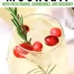 sparkling holiday mocktail with cranberries and a sprig of thype