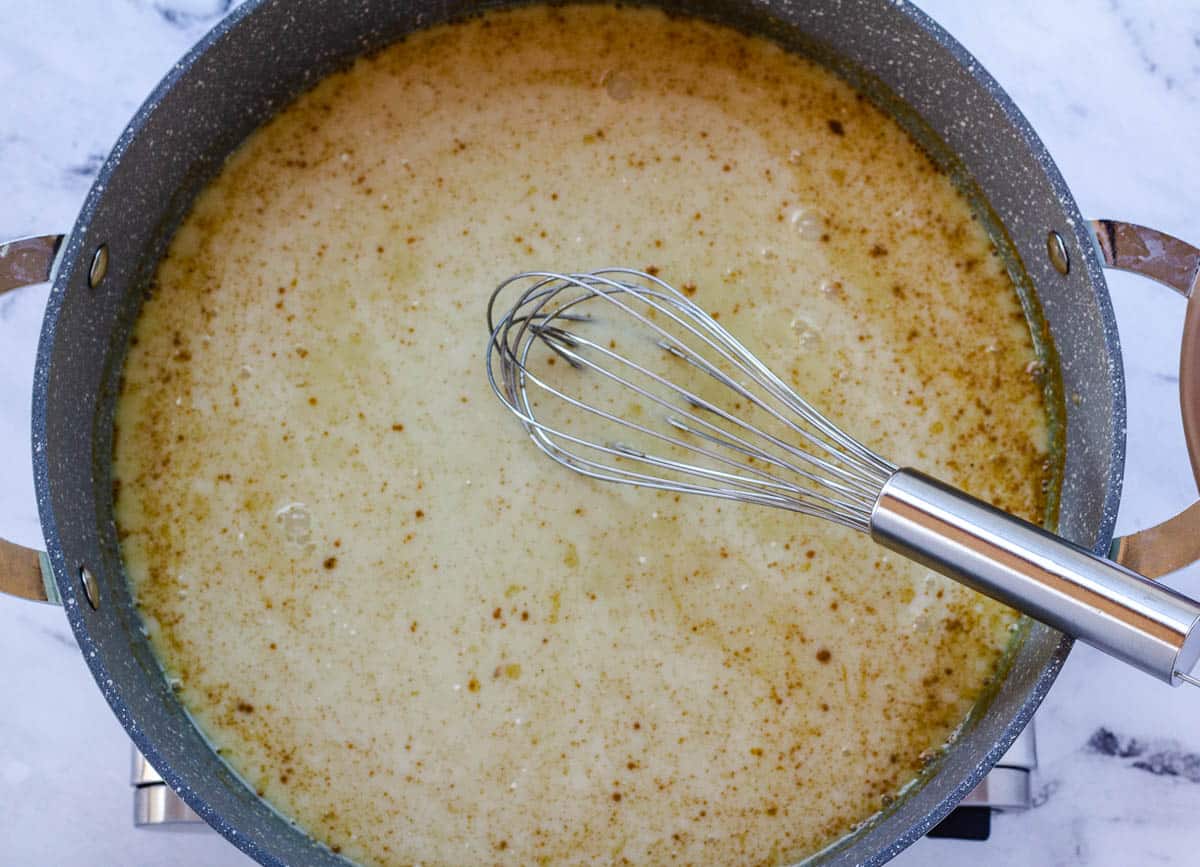 Coconut milk and spices whisked together in pan.