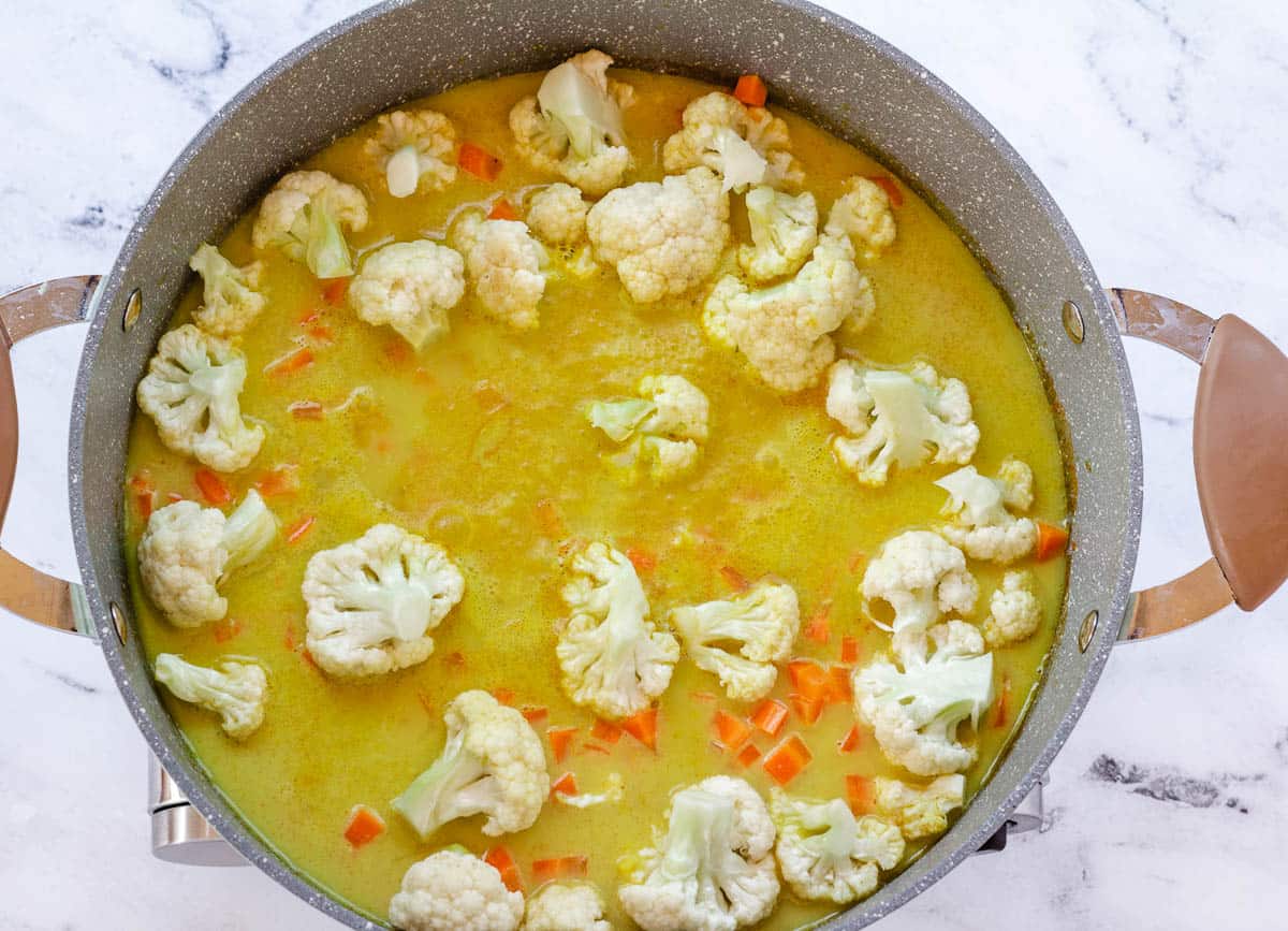 Cauliflower and carrots simmering in coconut milk curry sauce.