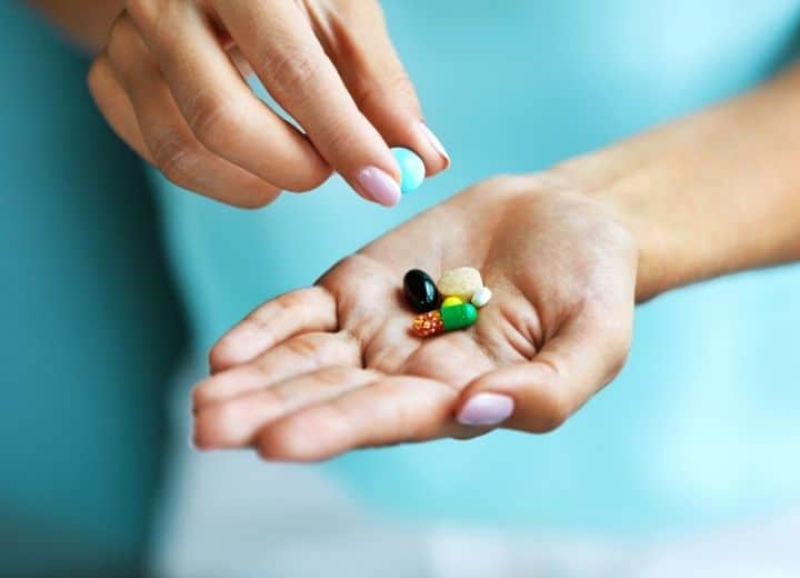 woman's hand holding several colorful vitamins