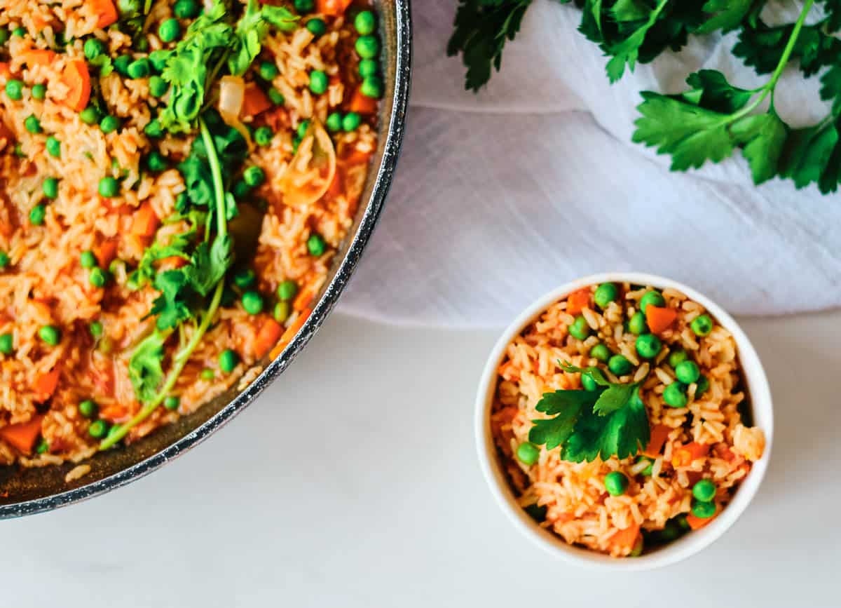 arroz rojo in pot and small side in white bowl topped with cilantro