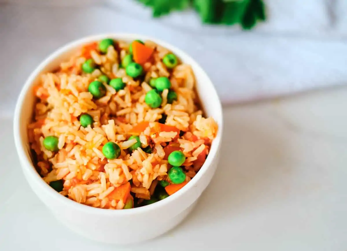 arroz rojo topped with green pea and carrots
