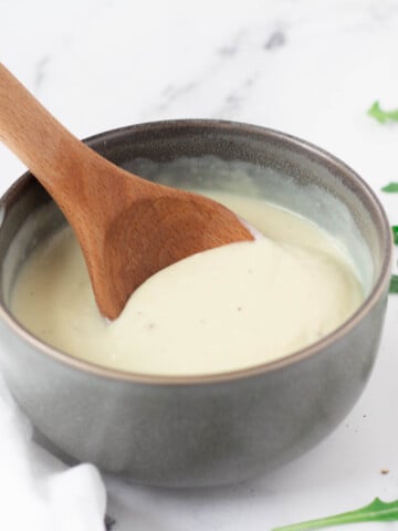vegan béchamel sauce in gray bowl with wooden spoon