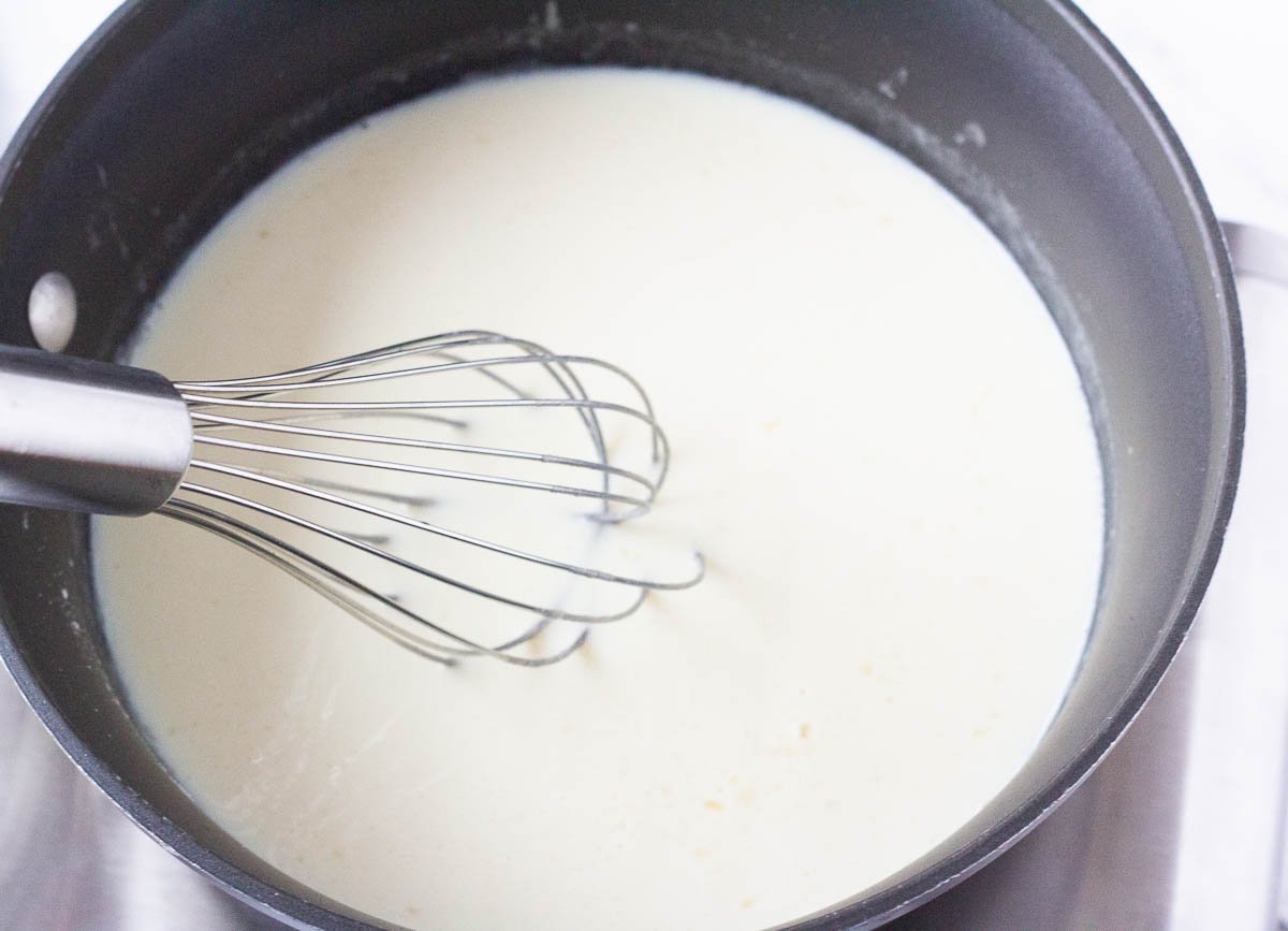 Soy milk whisking with roux in pot.
