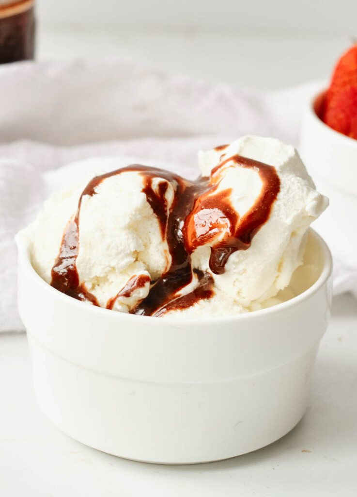 bowl of vanilla ice cream topped with vegan chocolate sauce 