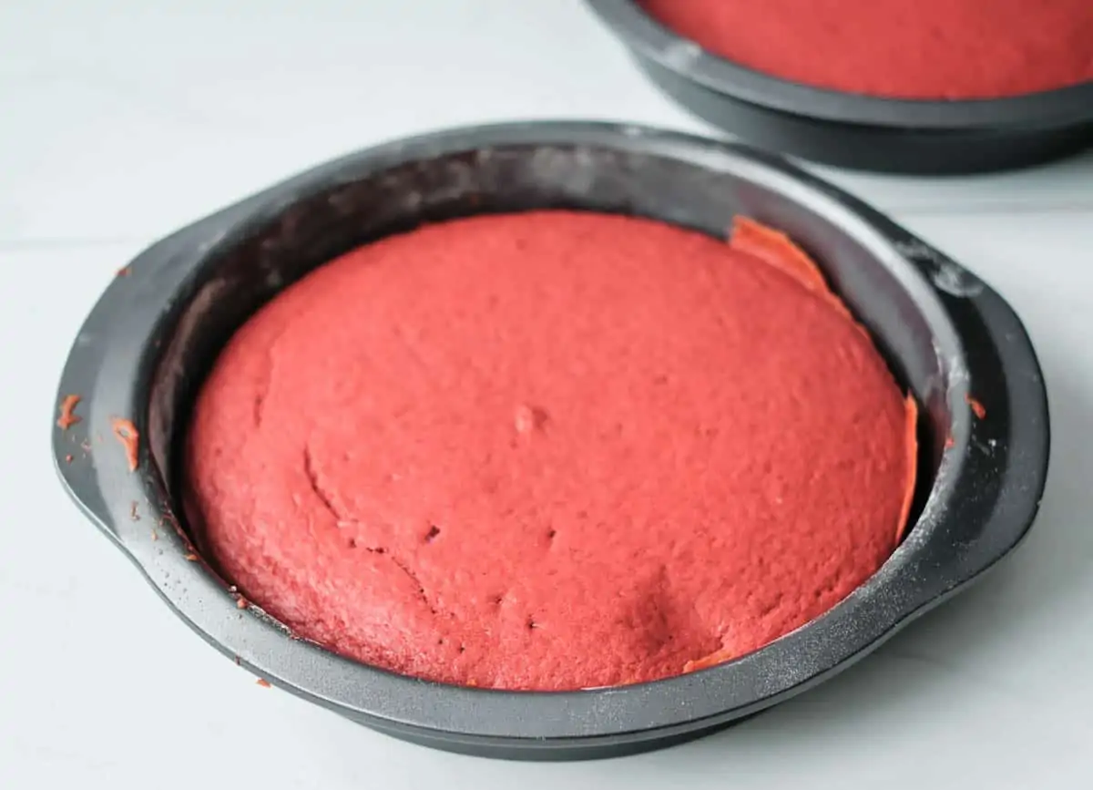 Baked red velvet cake cooling in cake pan.