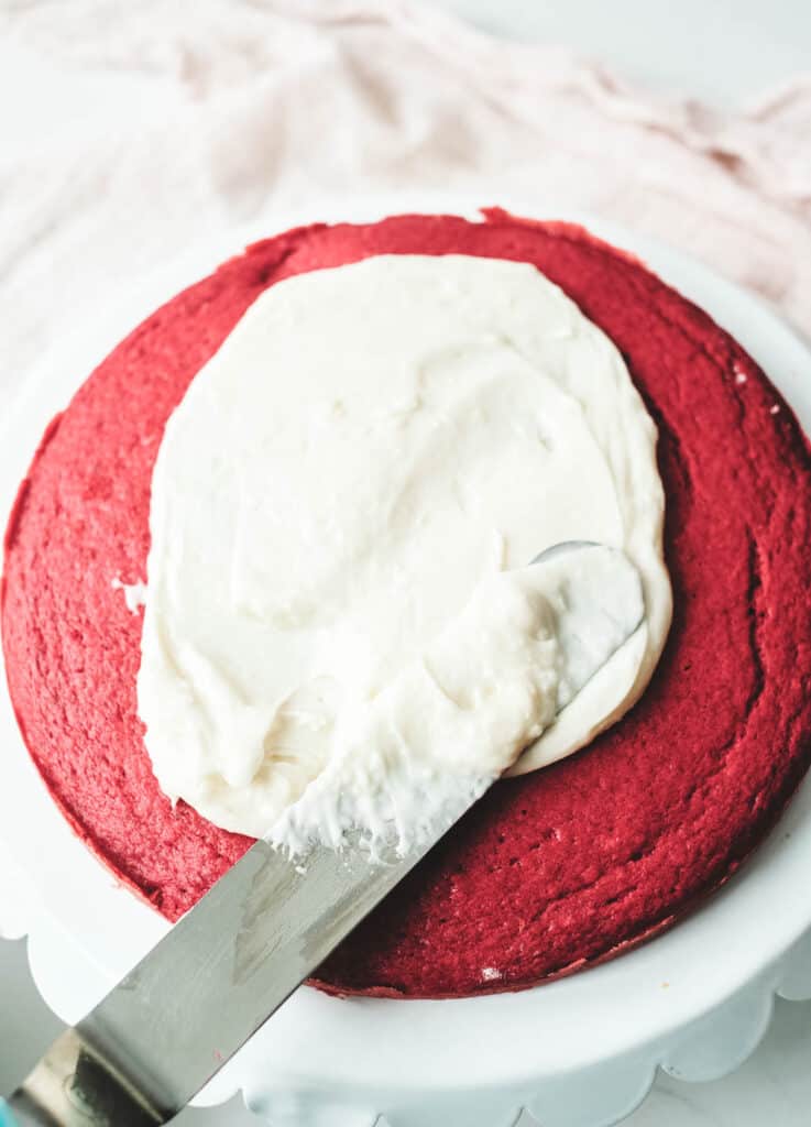 cream cheese frosting on top of layer of red cake