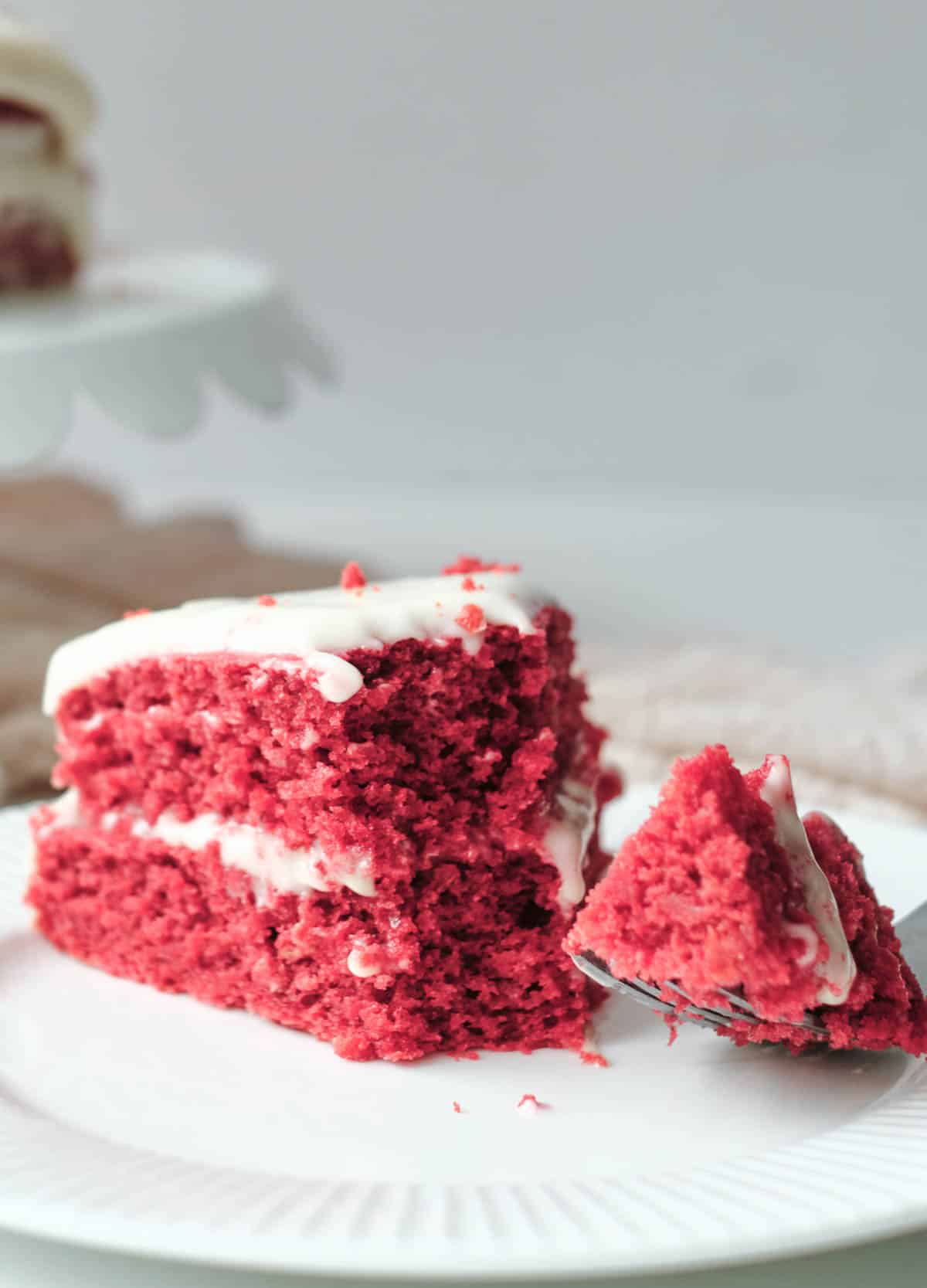 Slice of vegan red velvet cake on white plate. 