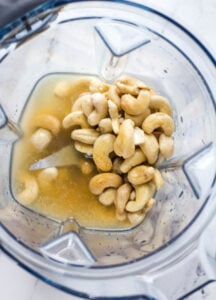 cashews and vegetable stock at the bottom of a blender
