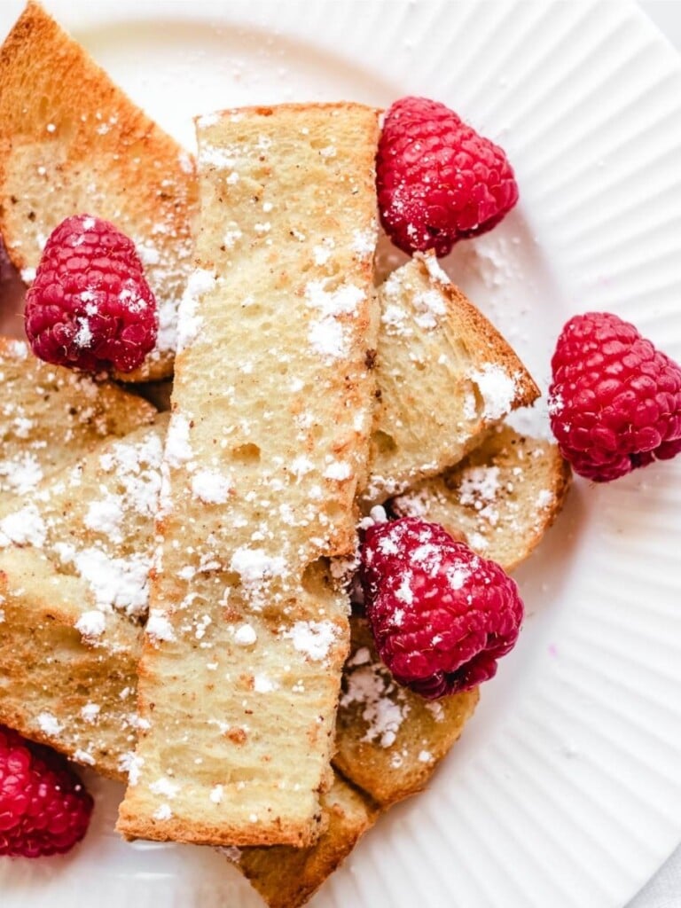 French toast sticks topped with raspberries, and powdered sugar.
