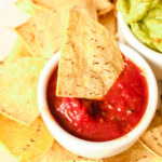 air fryer tortilla chip dipped in bowl of salsa