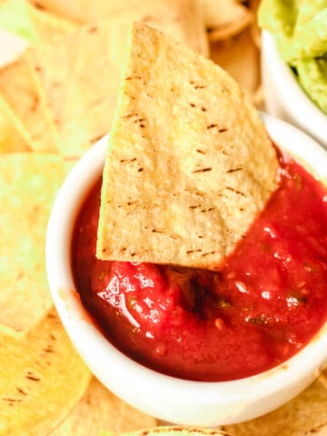 air fryer tortilla chip dipped in bowl of salsa