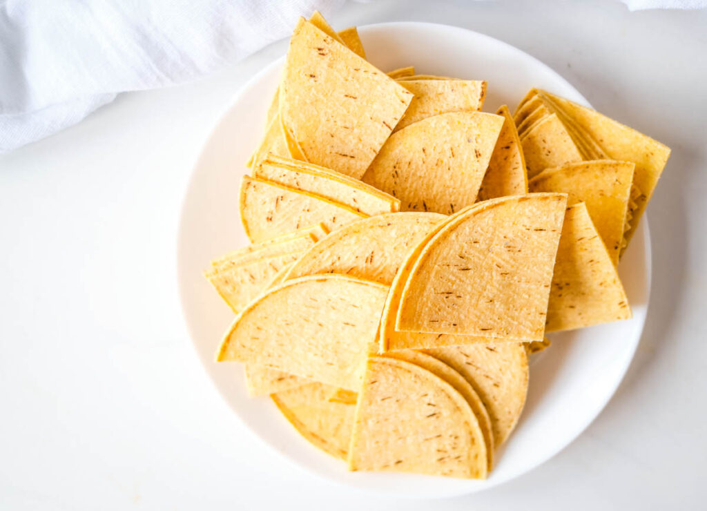 Corn tortillas cut into triangles on white plate.