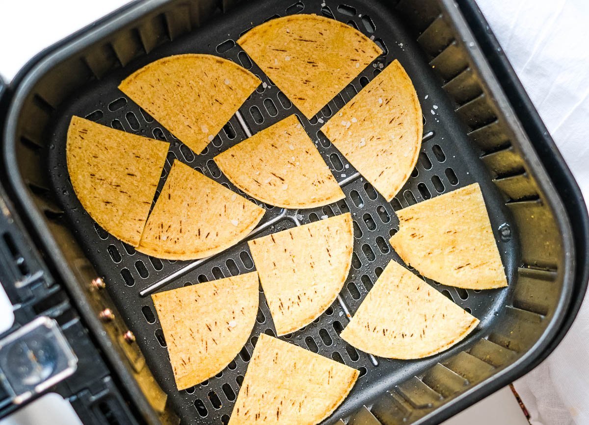 Tortilla triangles in air fryer basket. 