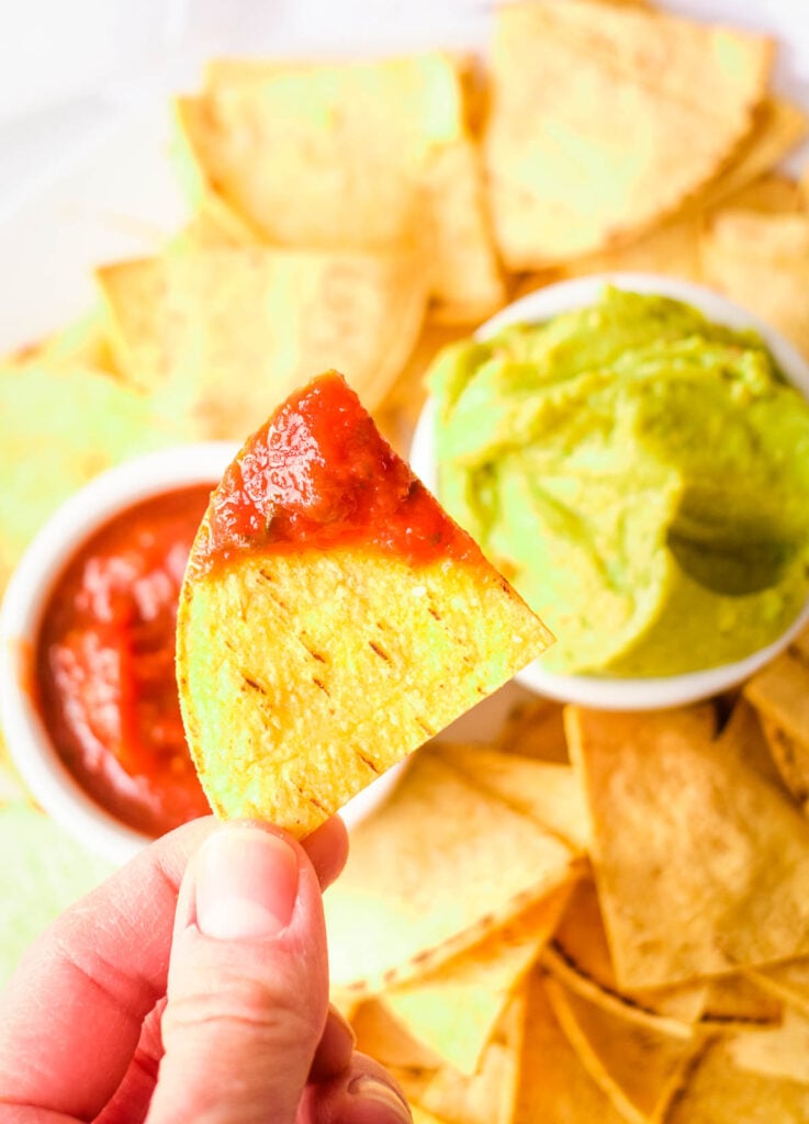 Hand holding chip dipped in salsa.