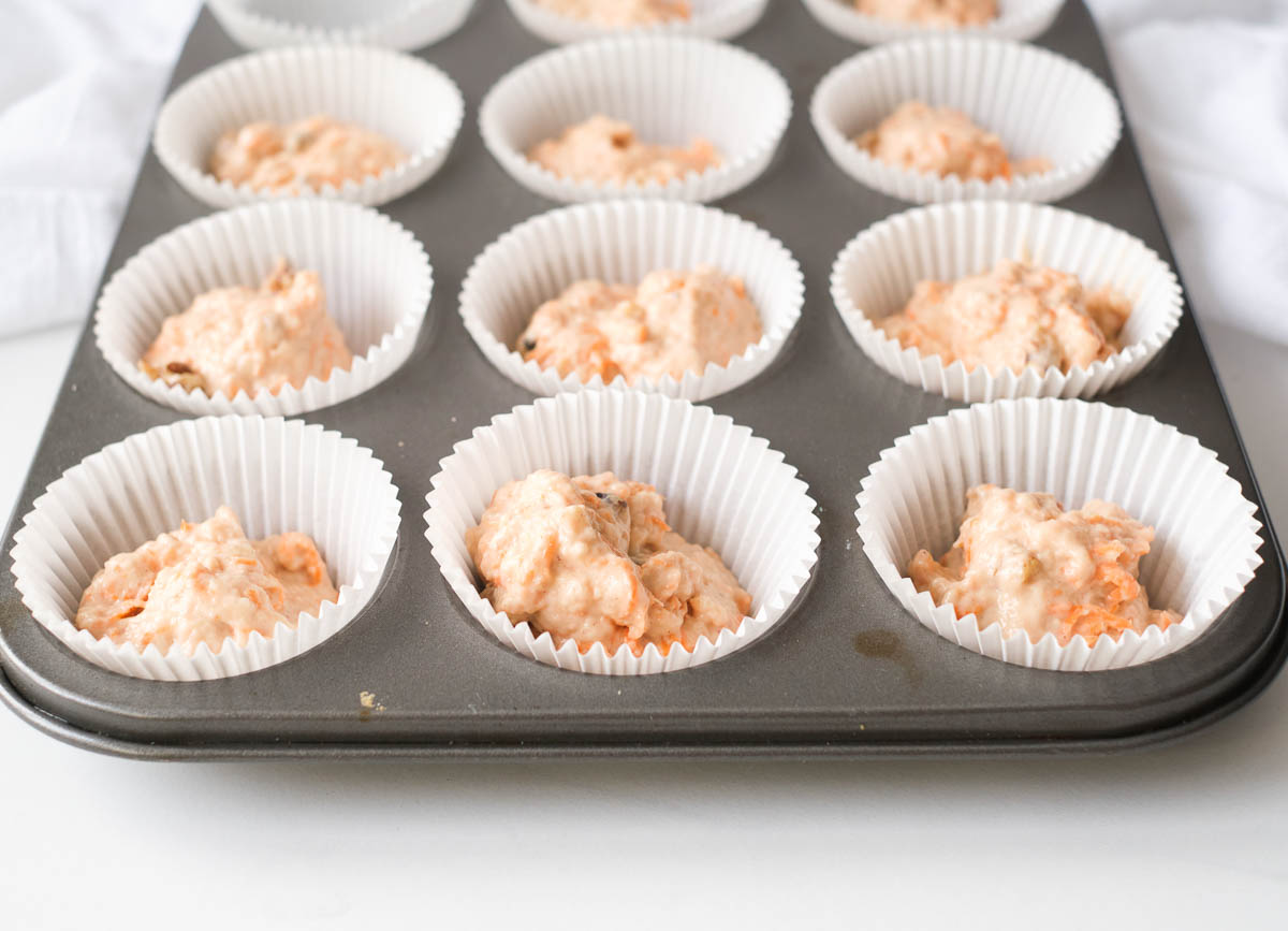 Muffin tin filled with carrot cake batter,