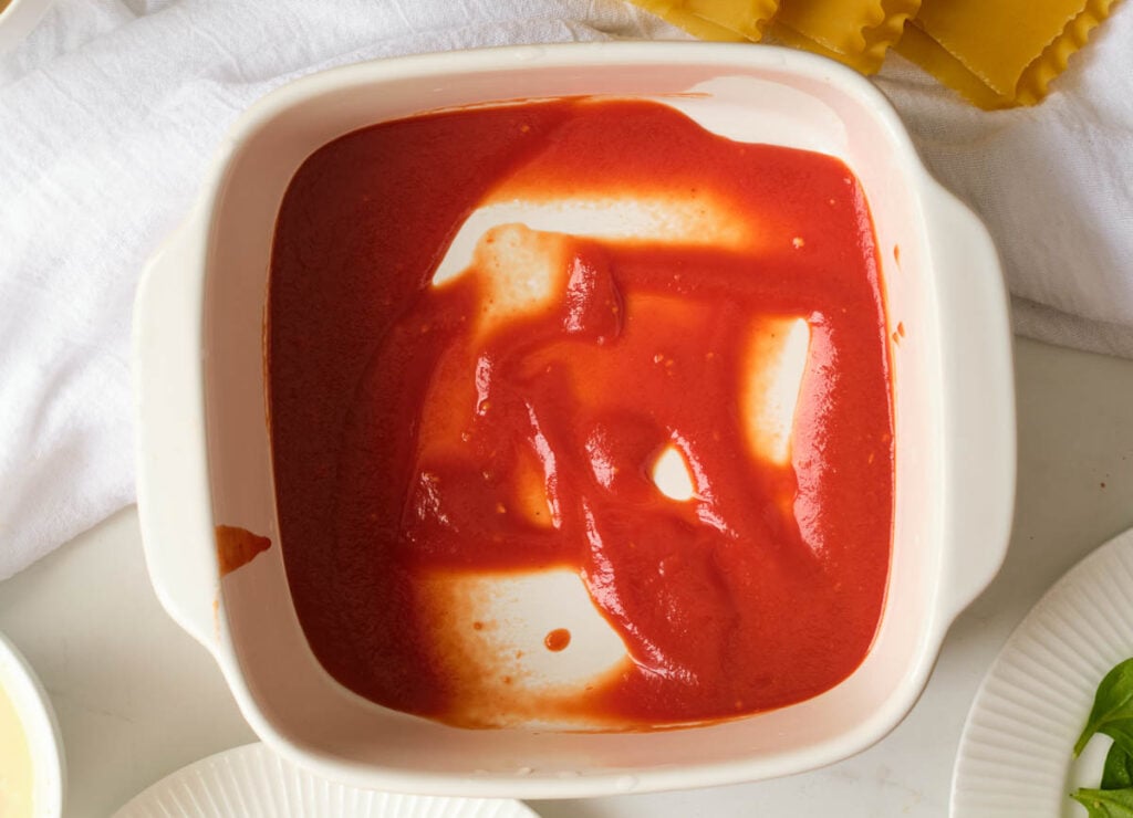 marinara sauce at the bottom of a casserole dish