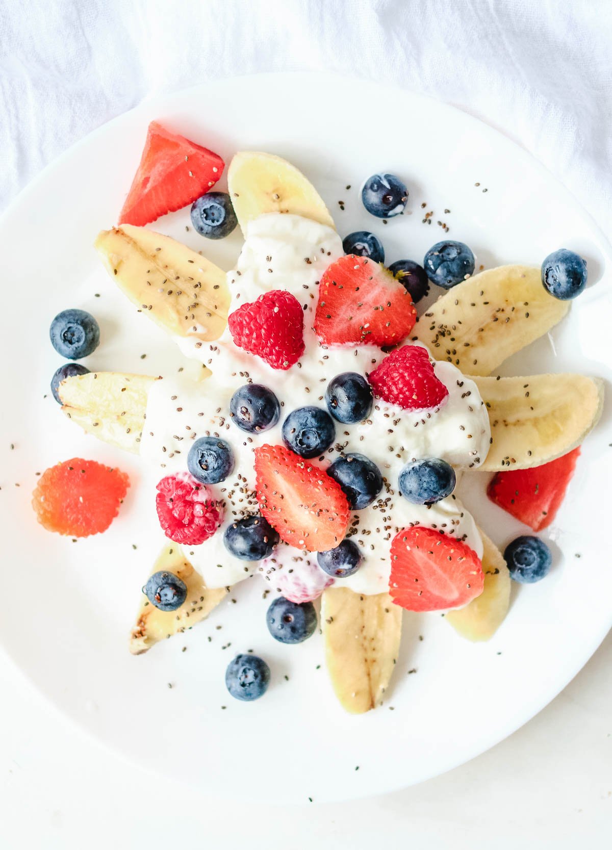 sliced bananas topped with vegan yogurt and fresh berries