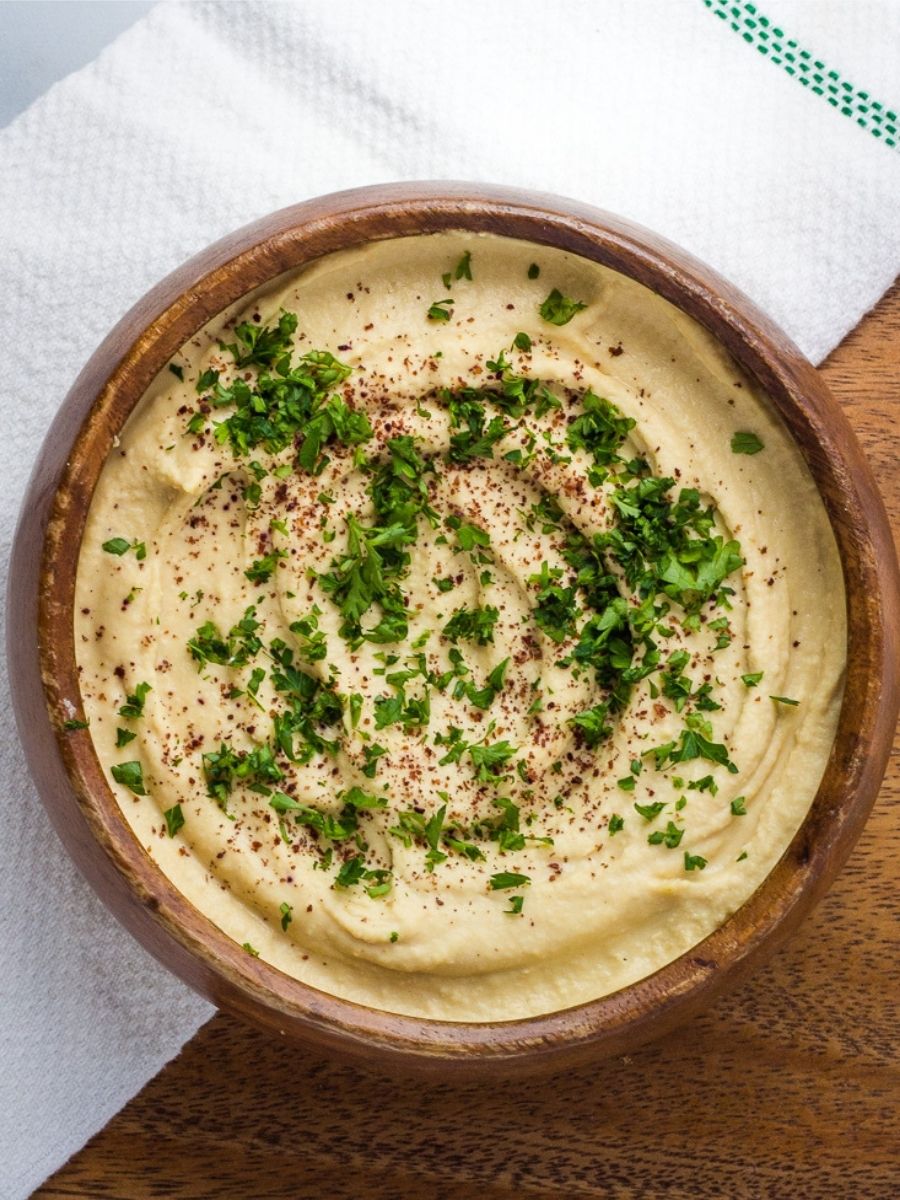 Homemade hummus dip topped with spices and fresh chopped parsley.