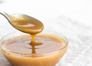 thick caramel sauce on spoon over bowl