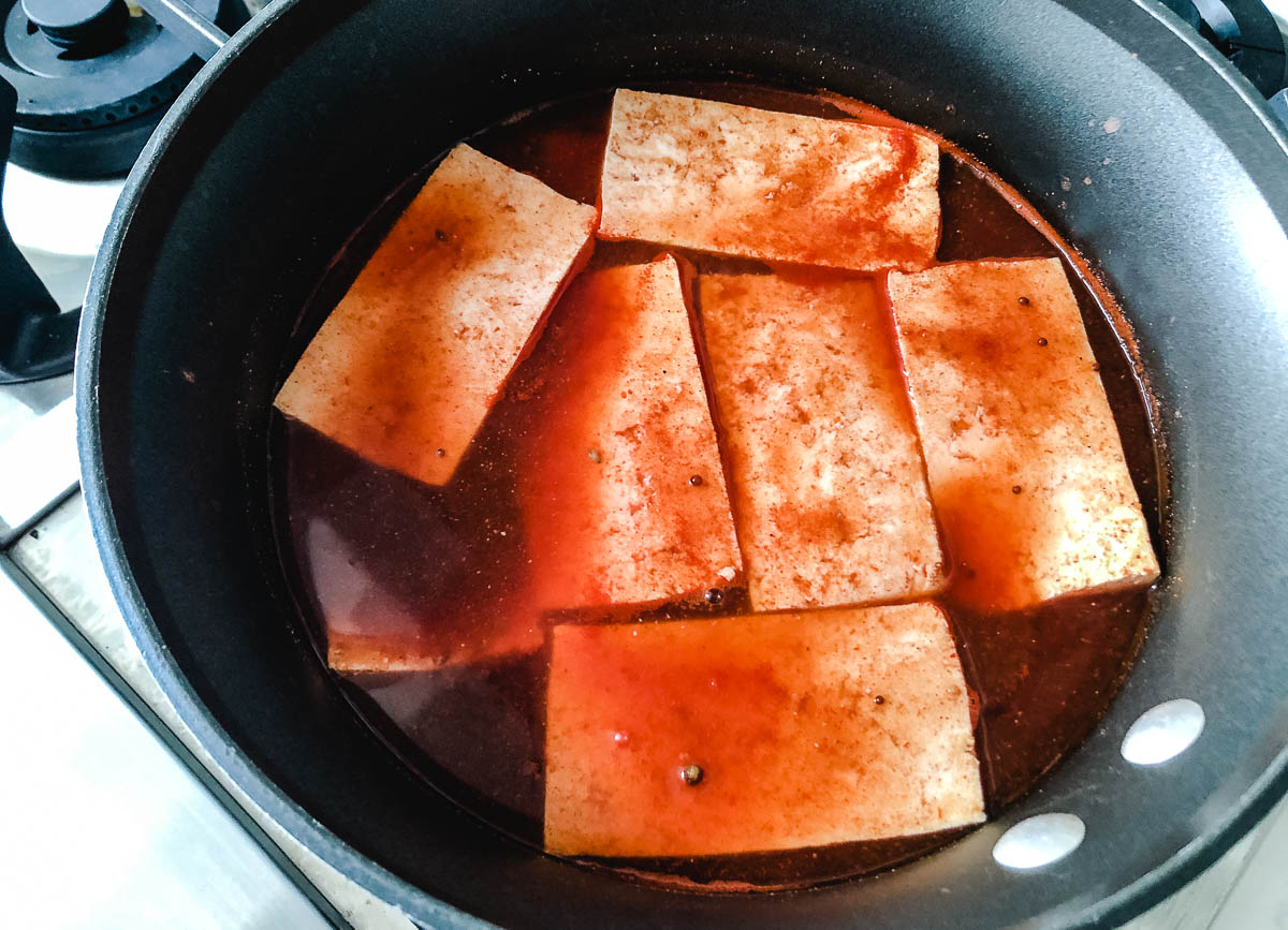 tofu marinating in pot with red sauce
