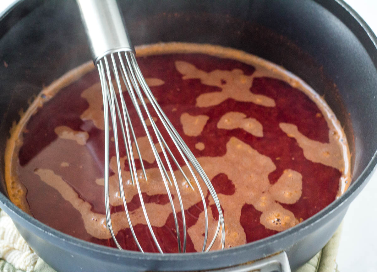 whisk in pot with red sauce