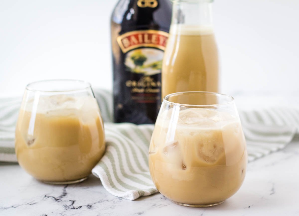 vegan Irish cream in two stemless wine glasses with Bailey's bottle in the background