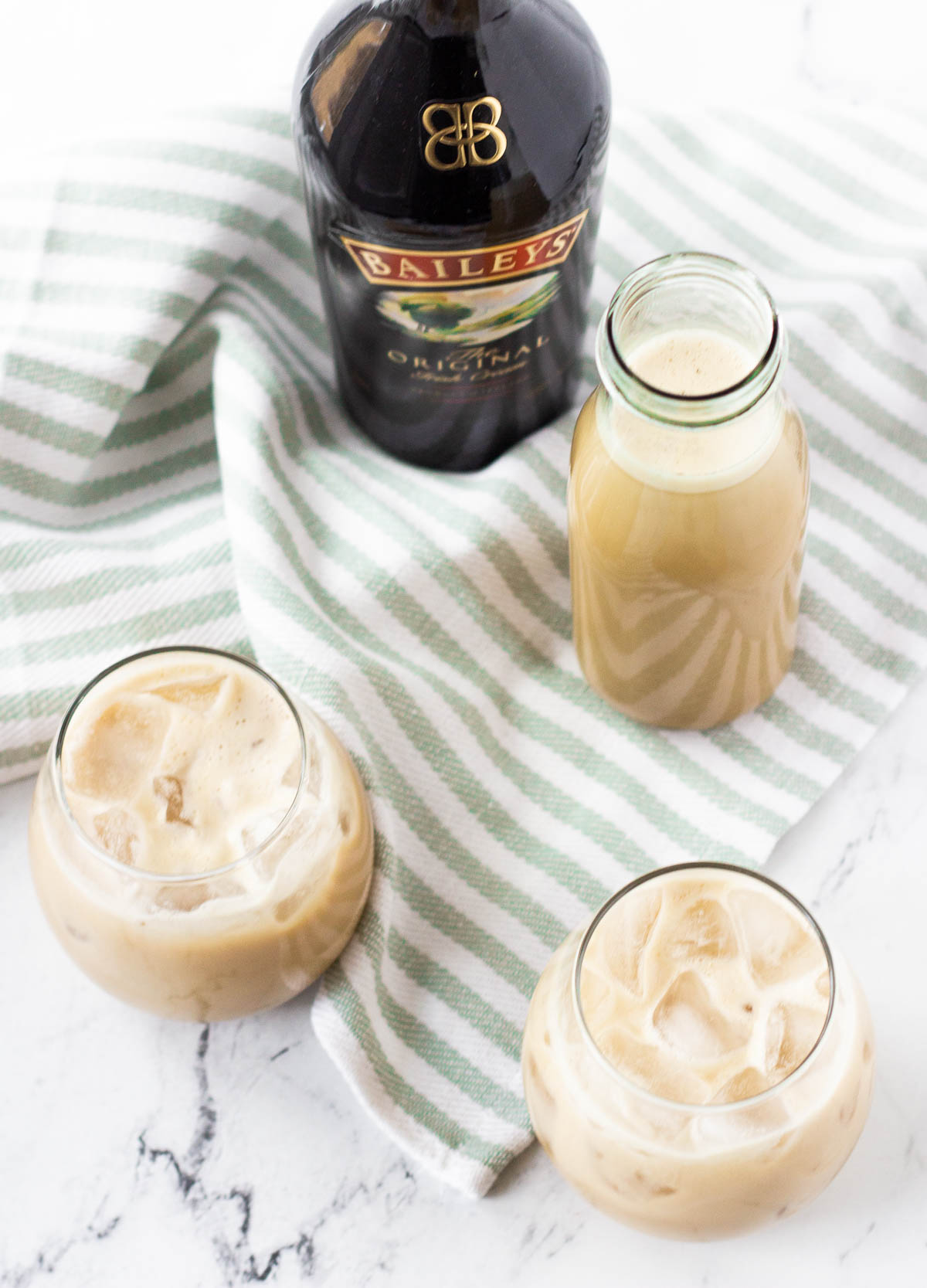 overhead of vegan Irish cream in stemless wine glasses with Bailey's bottle in the background