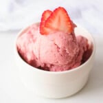 vegan strawberry ice cream in white bowl topped with strawberry slices