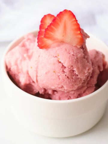 vegan strawberry ice cream in white bowl topped with strawberry slices