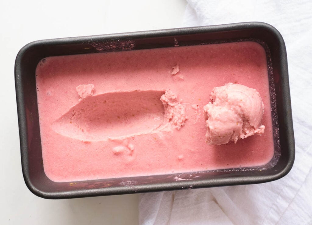 strawberry ice cream, frozen in loaf pan with scoop on top.