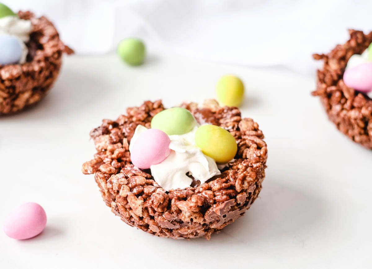 Birds nest cookies with chocolate rice cereal nest, gilled with chocolate ganache and topped with whipped cream and candy eggs.