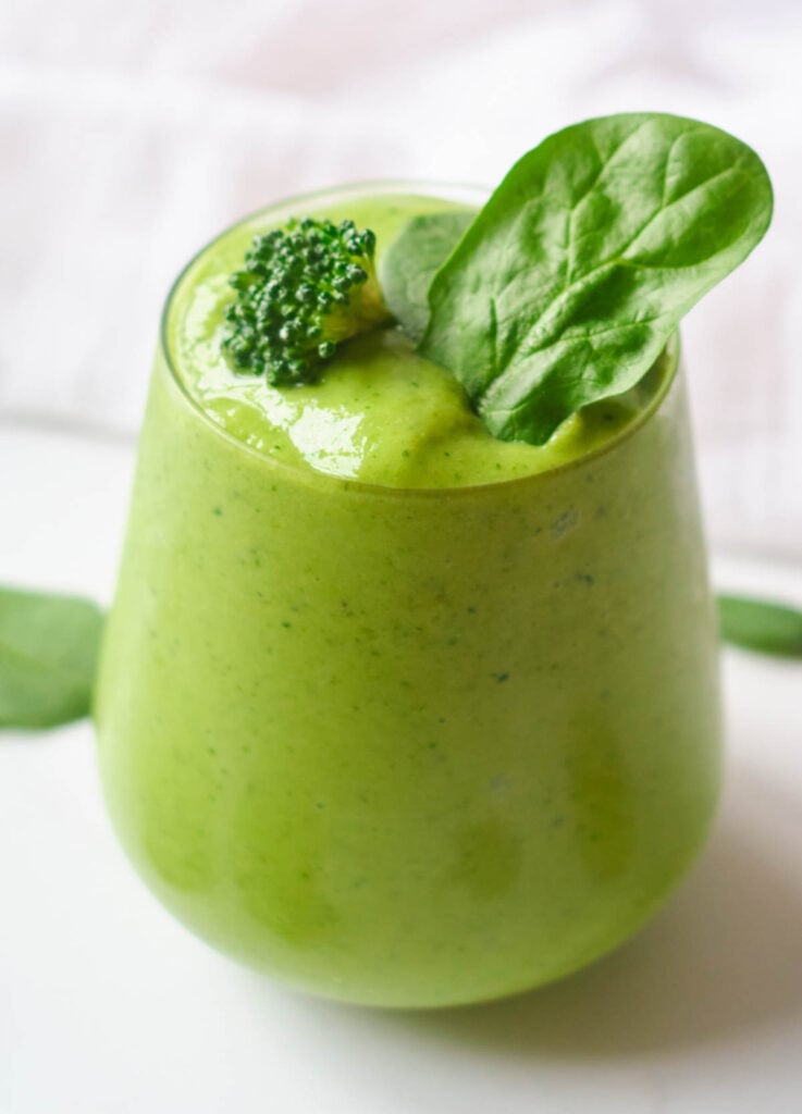 broccoli smoothie topped with broccoli floret and spinach leaves