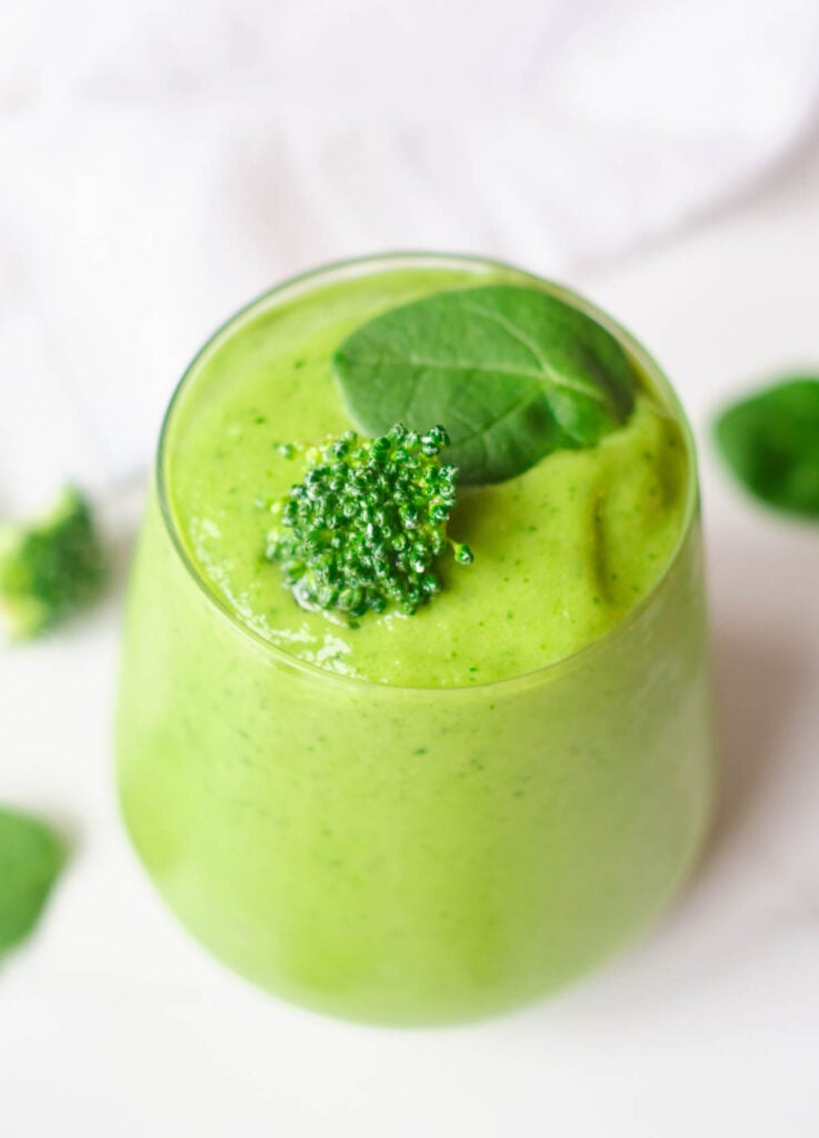 green smoothie topped with broccoli floret and spinach leaf