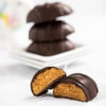 Chocolate peanut butter easter egg cut in half, with a stack of three more in the background.