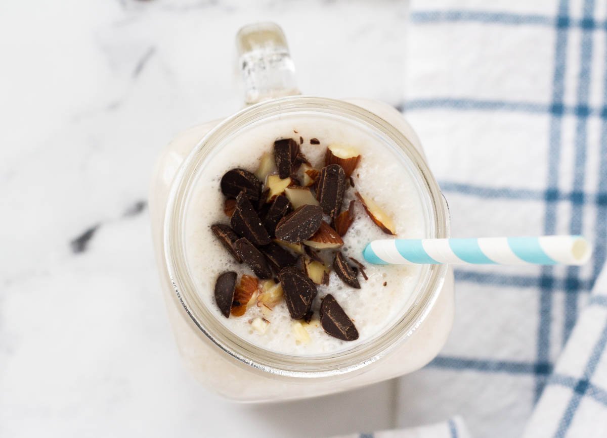 Coconut smoothie overhead topped with chocolate and almonds.