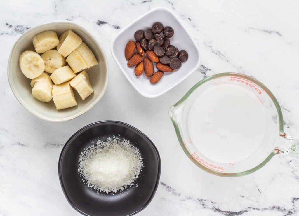 vegan milkshake ingredients: frozen banana, coconut milk, desiccated coconut, optional chocolate chips and almonds