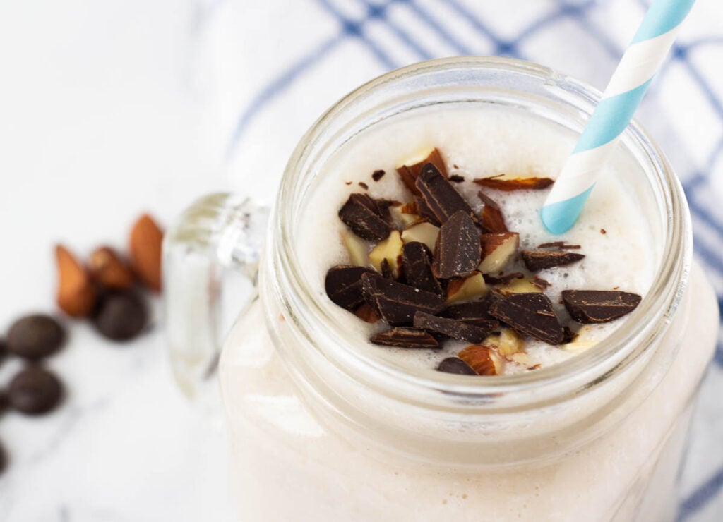top of almond joy coconut milkshake in glass mug topped with chocolate and almonds