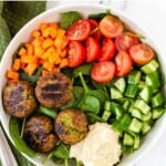 spinach topped with falafel, hummus, cucumbers, tomatoes, and carrots