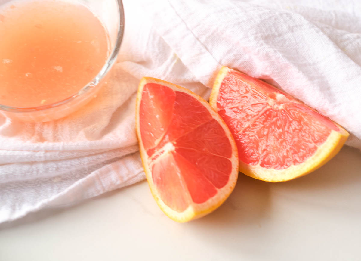 sliced grapefruit beside bowl of freshly squeezed grapefruit juice