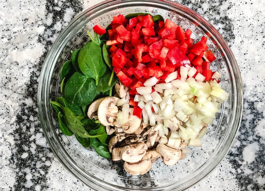 diced red peppers, spinach, mushrooms, and onion in glass bowl