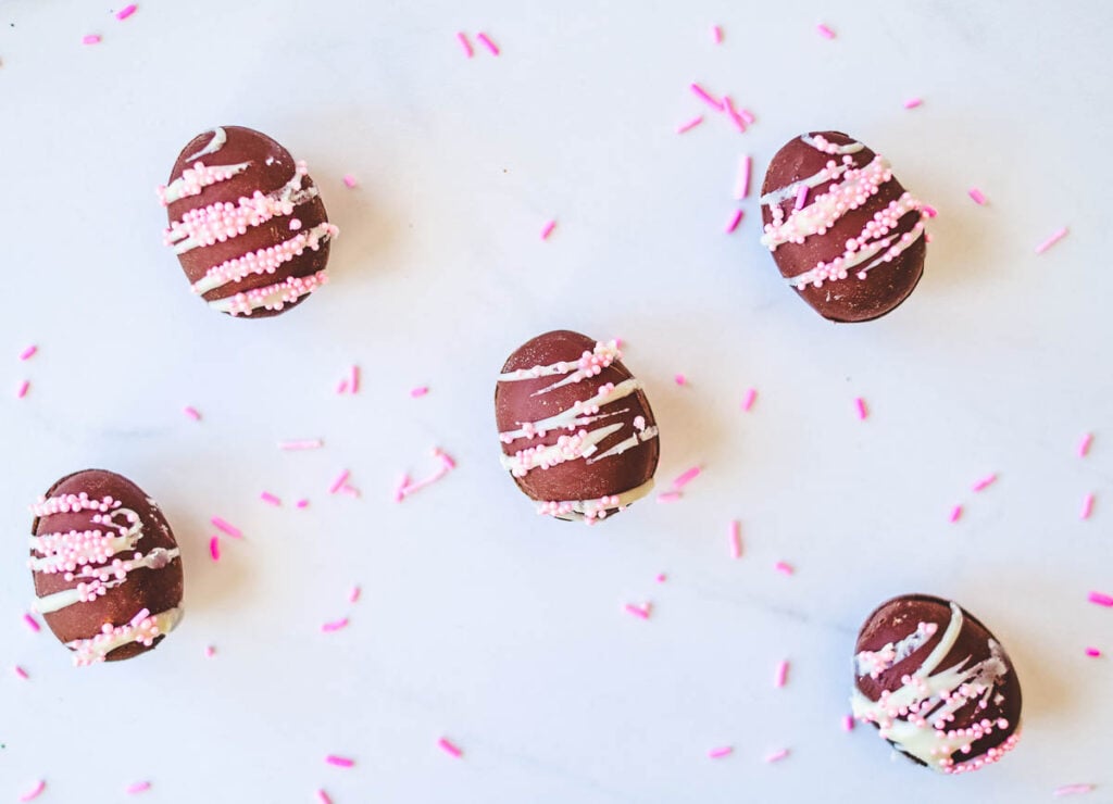 chocolate vegan easter egg with white frosting drizzle and pink sprinkles