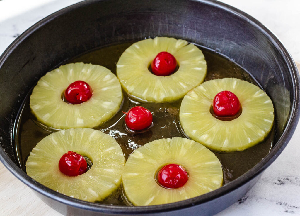 pineapple slices and cherries on the bottom of a cake pan
