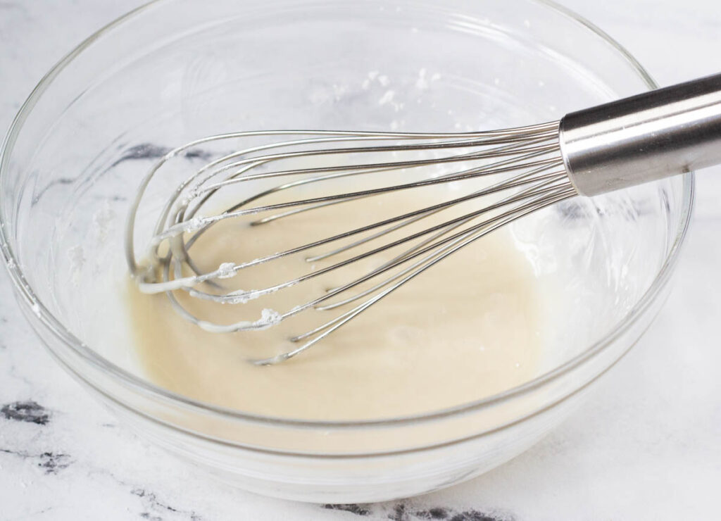 vanilla icing in glass bowl with whisk