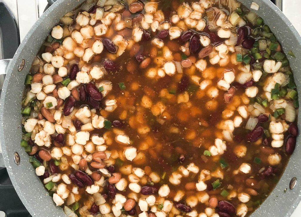 beans, hominy, and broth in pot simmering on the stove