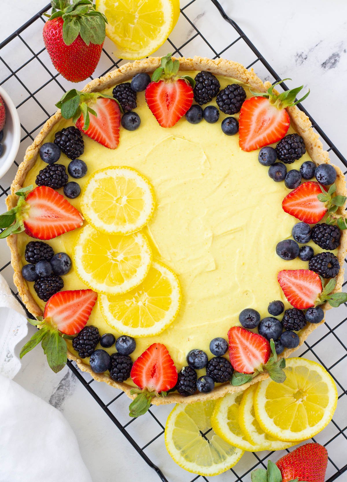 vegan lemon tart with fresh berries and lemon slices