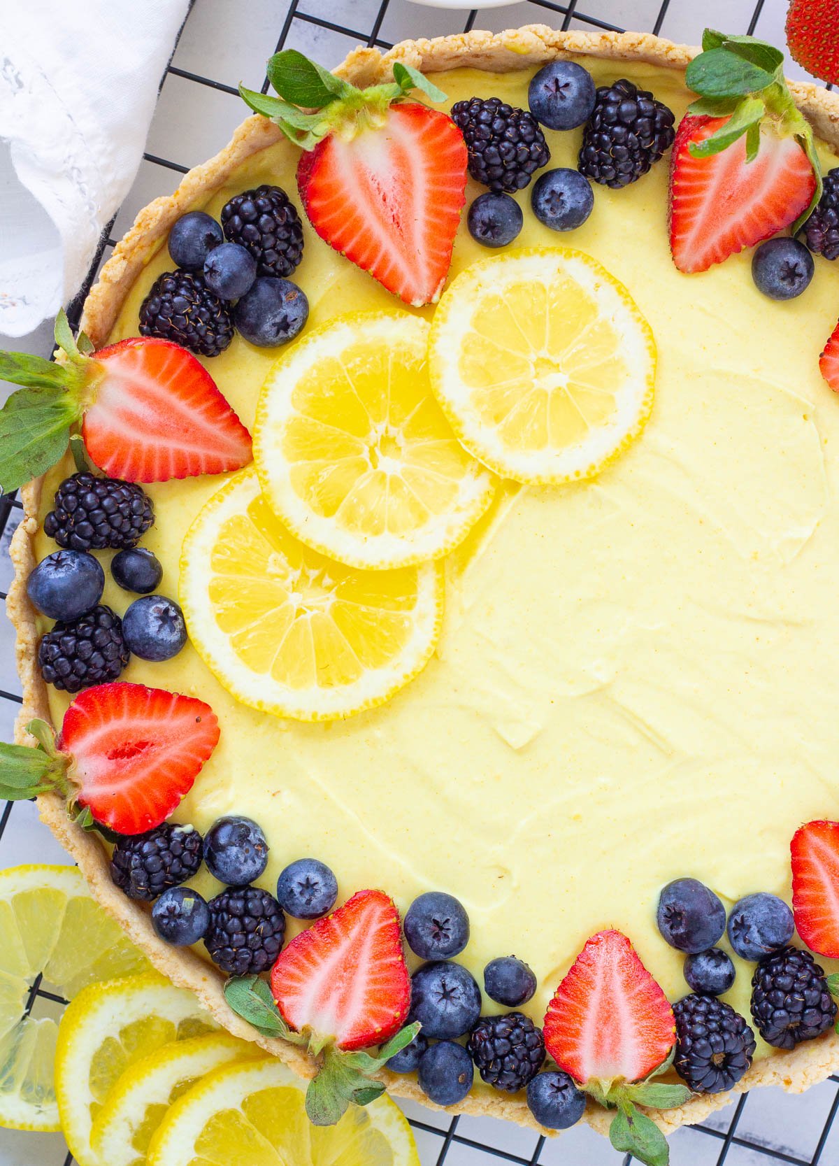 Vegan tart topped with lemon slices, and fresh berries.