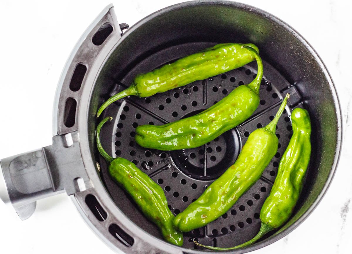 Shishito peppers in air fryer basket.
